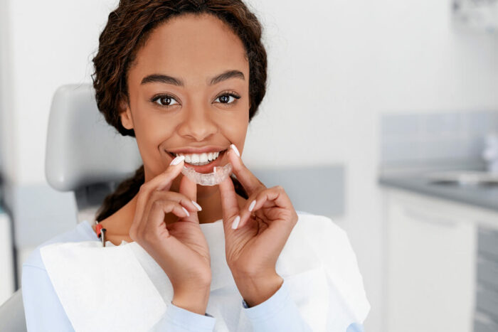 smiling woman holding a clear aligner