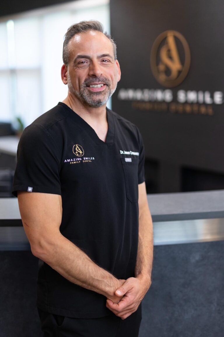 Dr. Jason Crescenzo headshot at Amazing Smiles lobby. Smiling and wearing black scrub suit