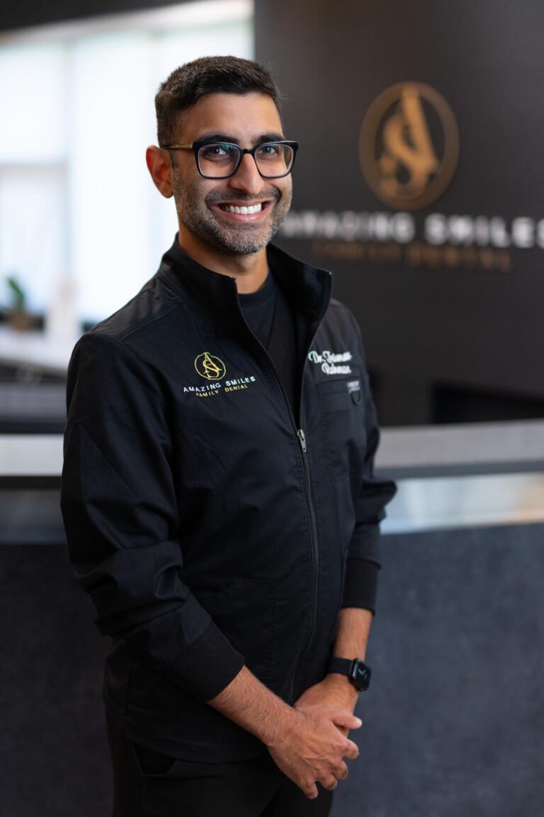 Dr. Taimoor Rahman headshot at Amazing Smiles lobby. Smiling and wearing black scrub suit