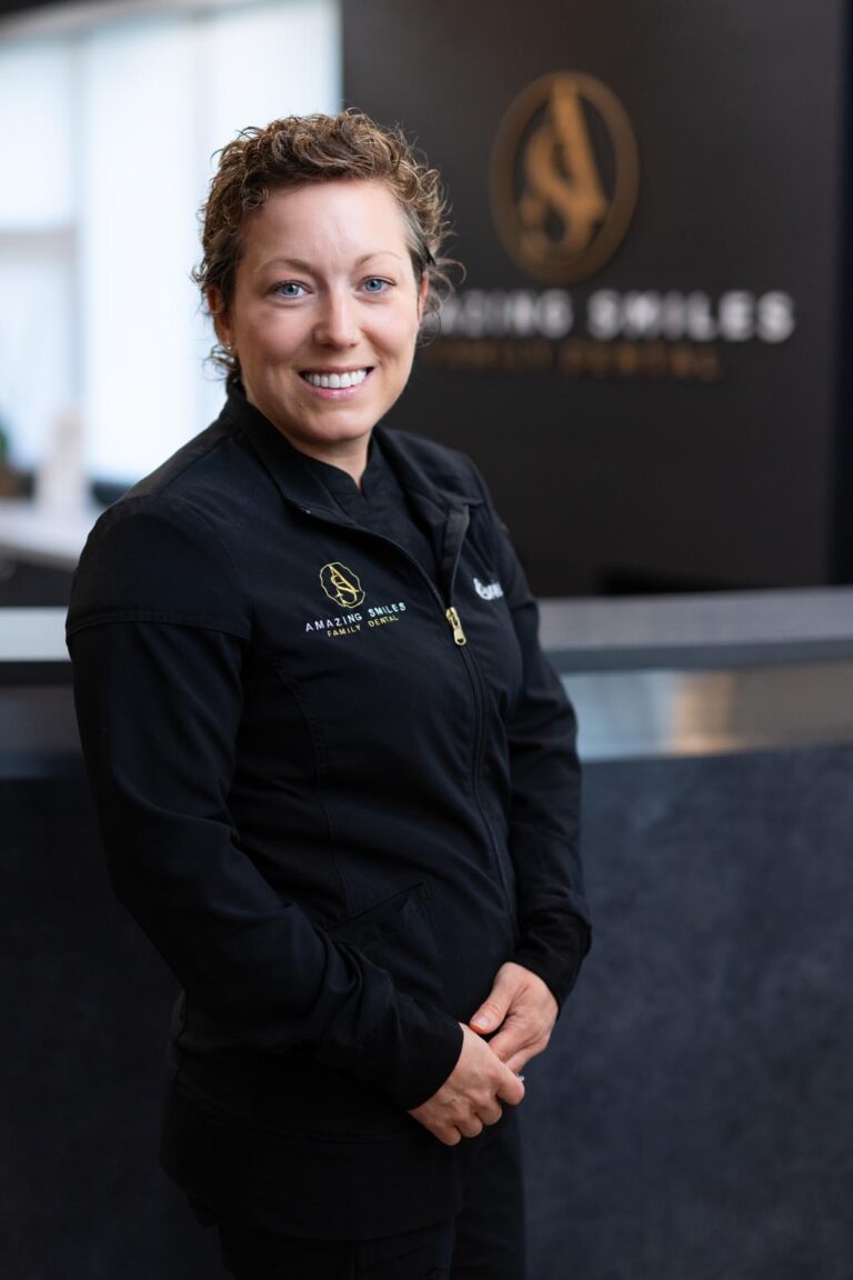 Corrie Clinical Lead headshot at Amazing Smiles lobby. Smiling and wearing black scrub suitDr. Emily