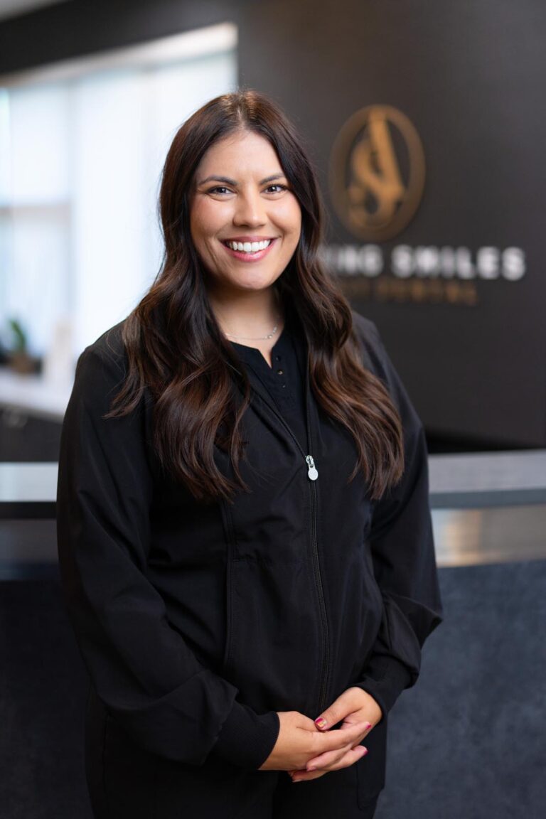 Dr Marissa Spica Orthodontist headshot at Amazing Smiles lobby. Smiling and wearing black scrub suit