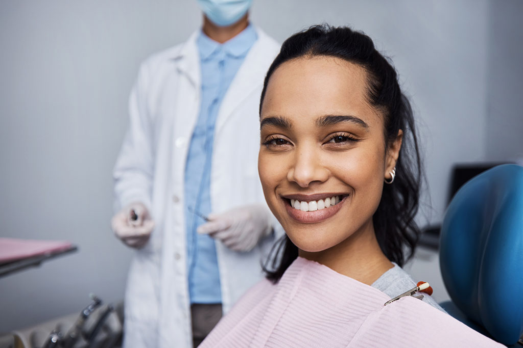 smiling woman with dentist behind