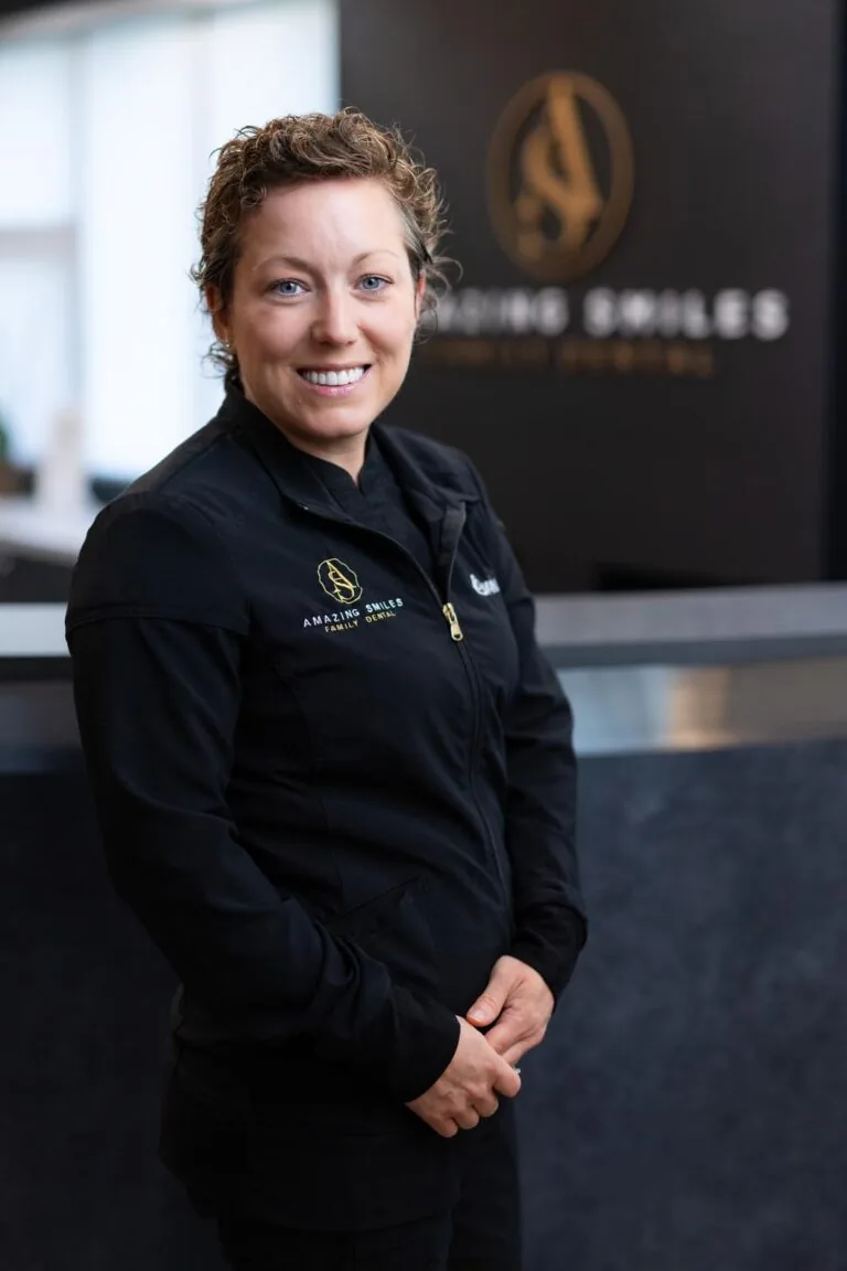 Corrie Clinical Lead headshot at Amazing Smiles lobby. Smiling and wearing black scrub suitDr. Emily
