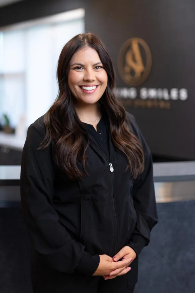 Dr Marissa Spica Orthodontist headshot at Amazing Smiles lobby. Smiling and wearing black scrub suit